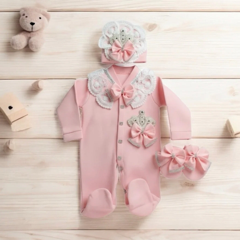 Pink baby romper with lace, bows, and crown design, paired with matching hat and booties
