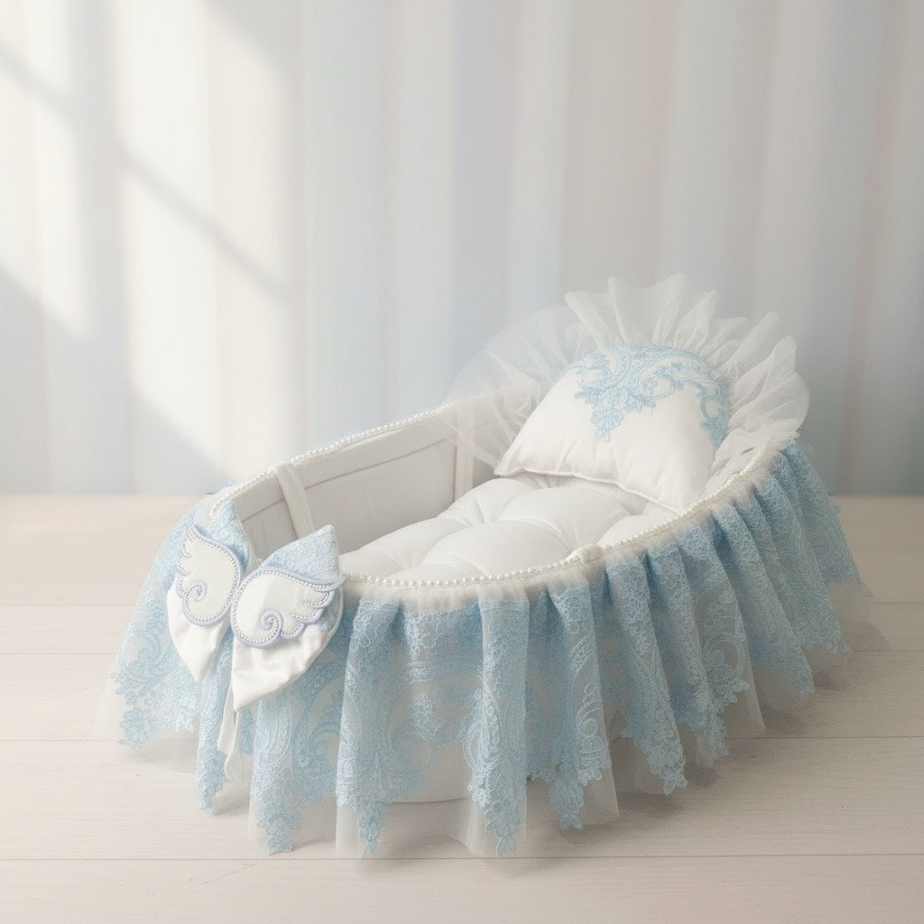 Luxury baby bassinet with blue lace, angel wings, and embroidered pillow for newborns