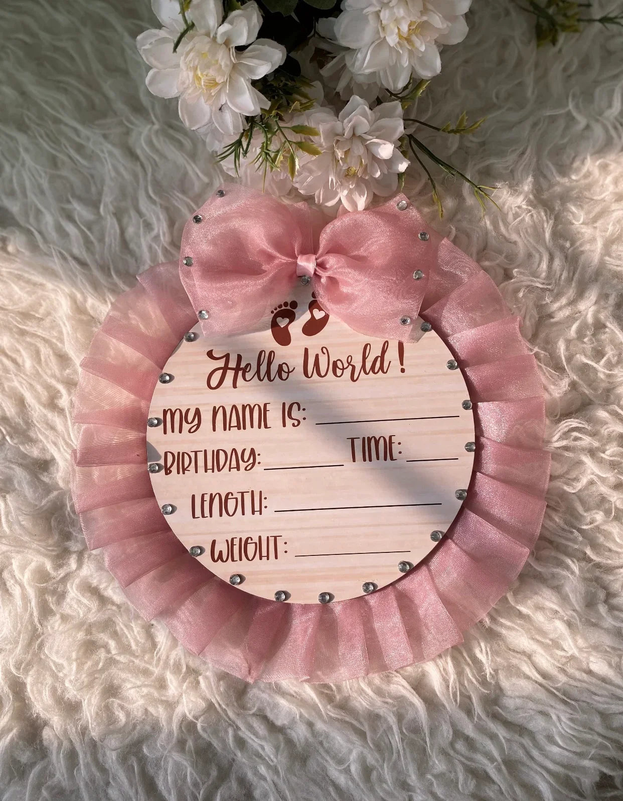 Pink baby birth announcement sign with 'Hello World' on fluffy rug, perfect for newborn photoshoots