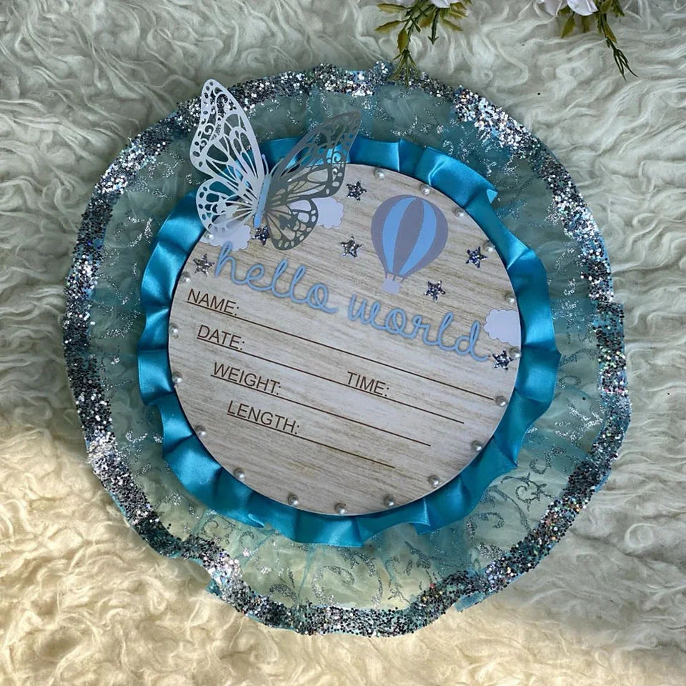 Hello World baby announcement plaque with butterfly, hot air balloon, blue ribbon, and glitter trim for newborn photoshoots