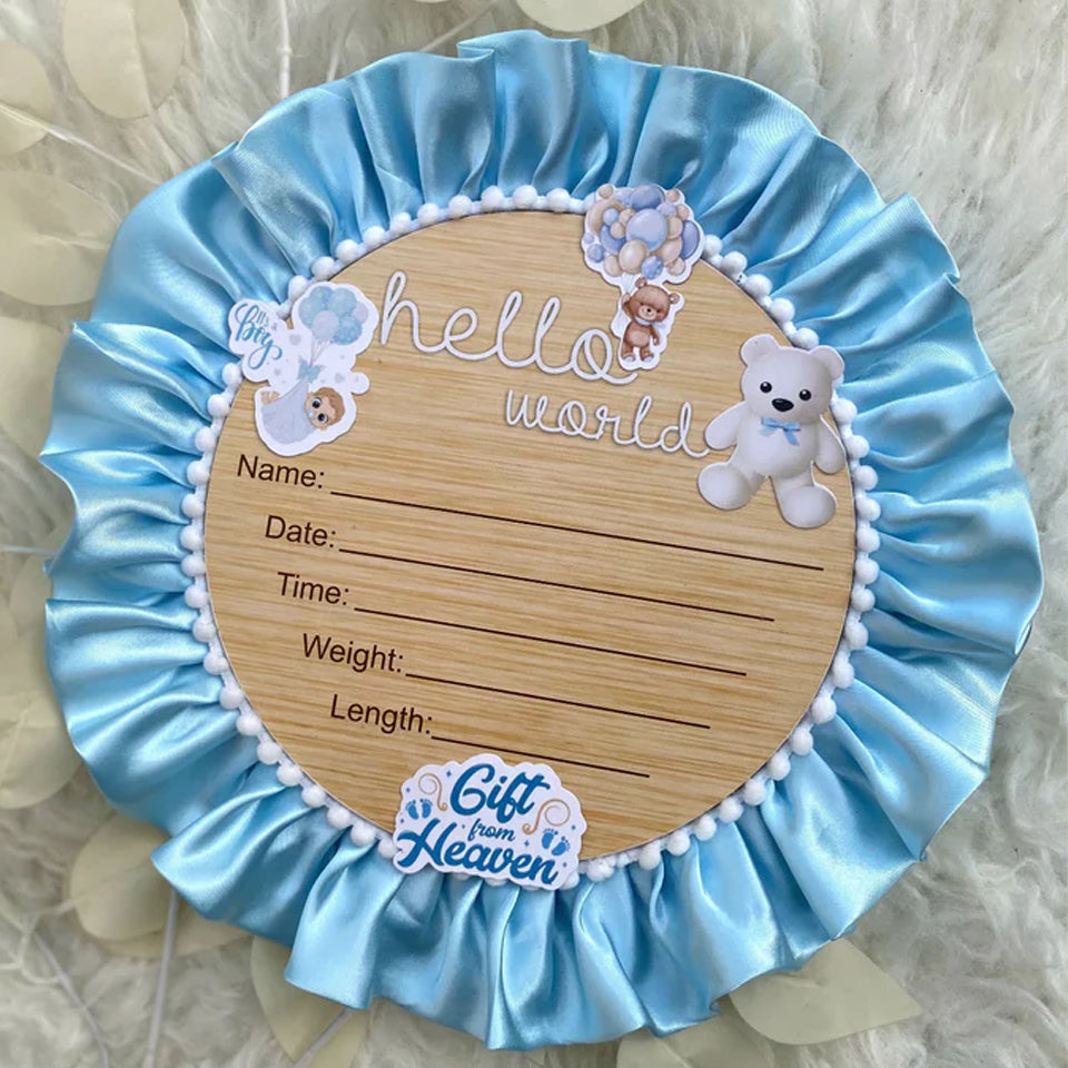 Hello World baby announcement board with teddy bear, blue satin trim, and 'Gift from Heaven' sticker
