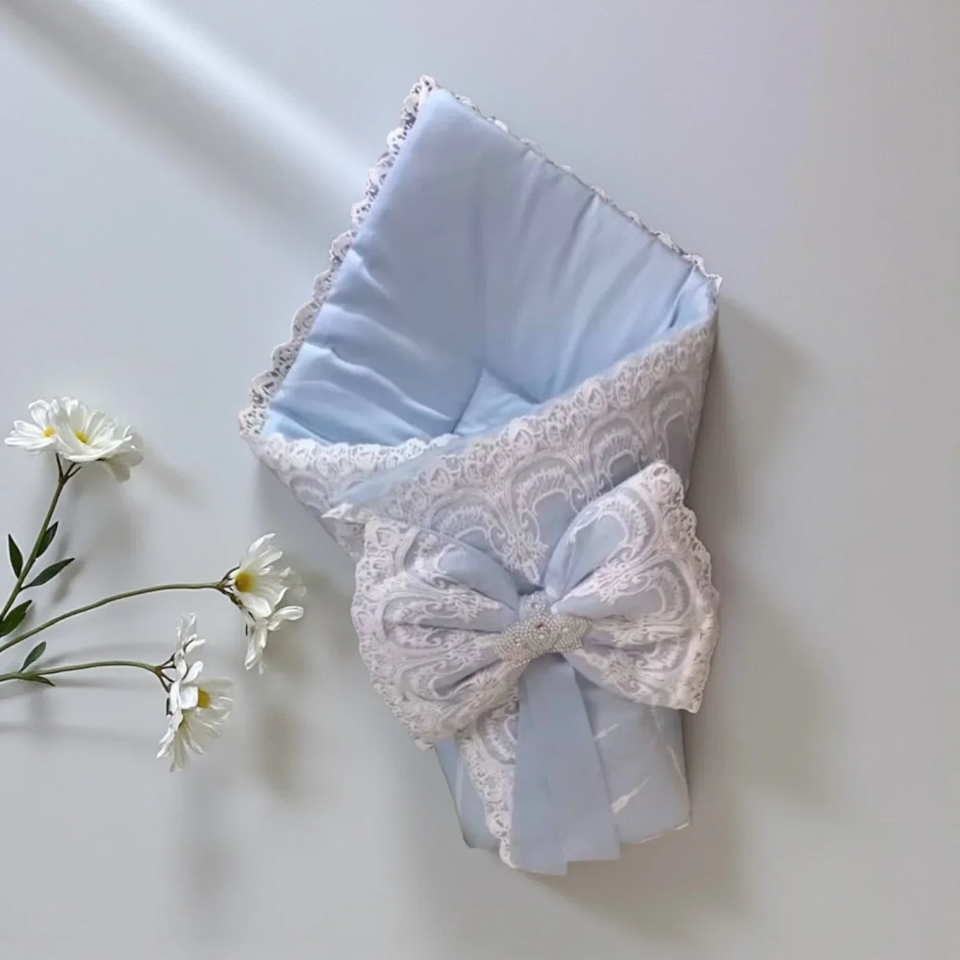 Delicate baby swaddle wrap with lace trim and bow, soft blue organic cotton for newborns