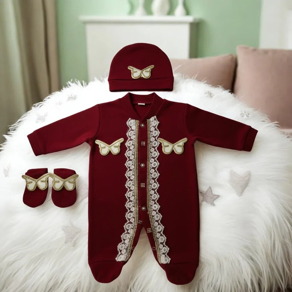 Luxury maroon baby romper set with lace, butterfly details, hat & booties on fluffy white rug