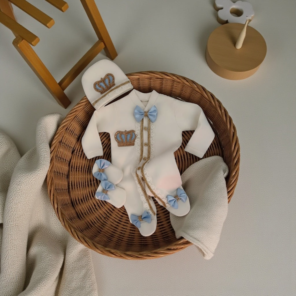 Luxury newborn baby romper set with crown embroidery, blue bows, and matching hat in wicker basket